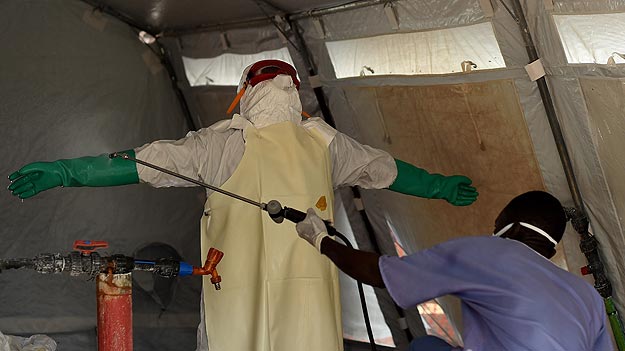 Un enfermero con un traje protector es desinfectado en Kenama, centro para el tratamiento del ébola en Sierra Leona